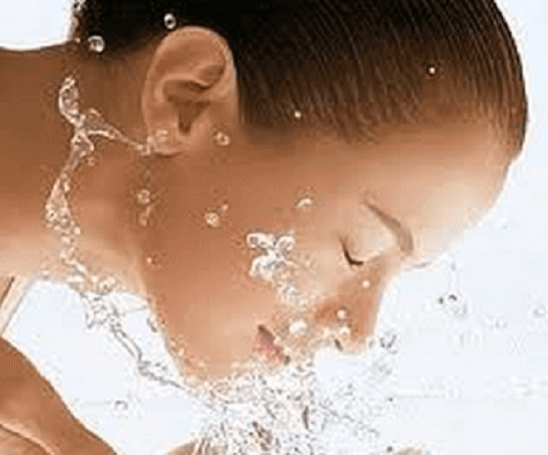 vrouw wast gezicht met water