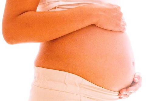 Zwangere vrouw houdt buik vast