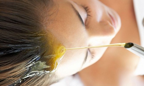 Vrouw giet olijfolie in het haar