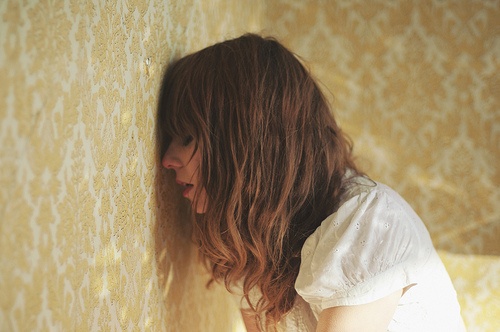 Vrouw leunt met hoofd tegen de muur