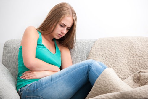 Vrouw op de bank met armen om buik geslagen
