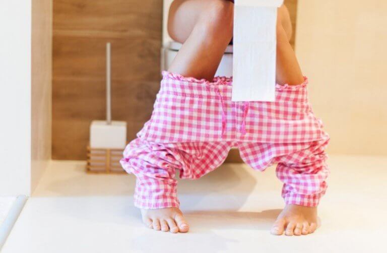 Vrouw met roze geruite broek op het toilet
