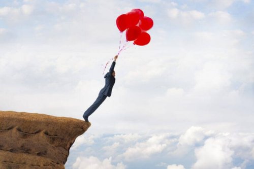Man met ballonnen die van een rots springt