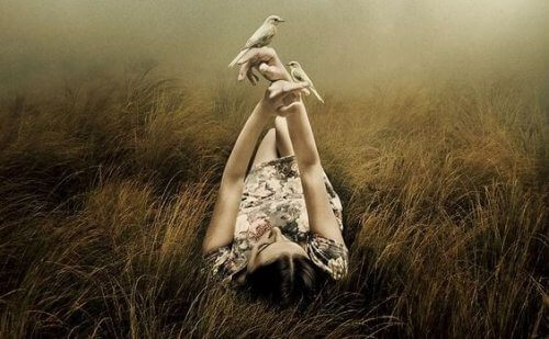 Vrouw die ontspannen in het gras ligt met twee vogels