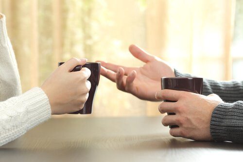 Twee mensen die onder het genot van een kop koffie met elkaar praten