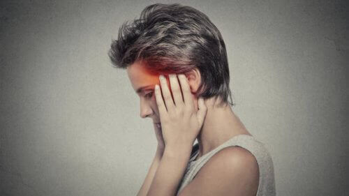 Vrouw die haar handen tegen haar slapen houdt omdat ze last heeft van nachtelijke hoofdpijn