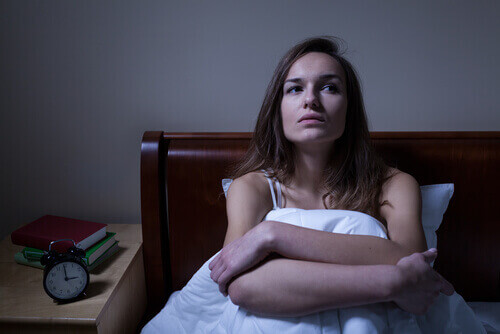 Vrouw die rechtop in bed zit omdat ze last heeft van nachtelijke paniekaanvallen