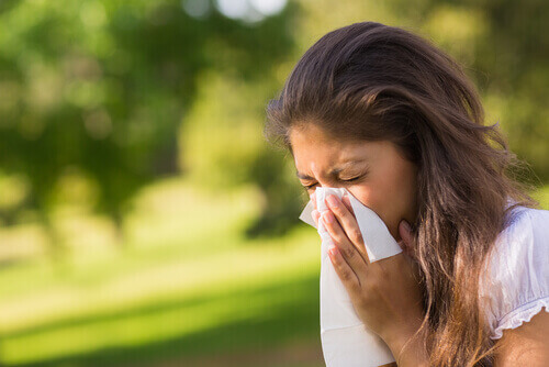 Vrouw die haar neus snuit omdat ze last heeft van de symptomen van sinusitis