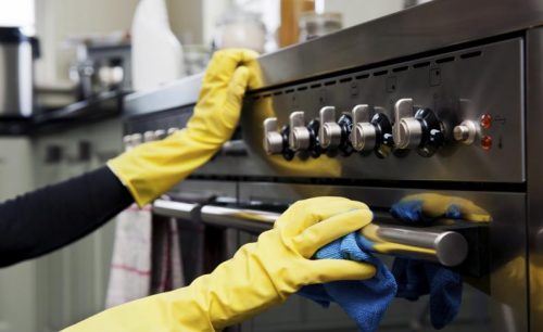 Vrouw die de oven schoonmaakt