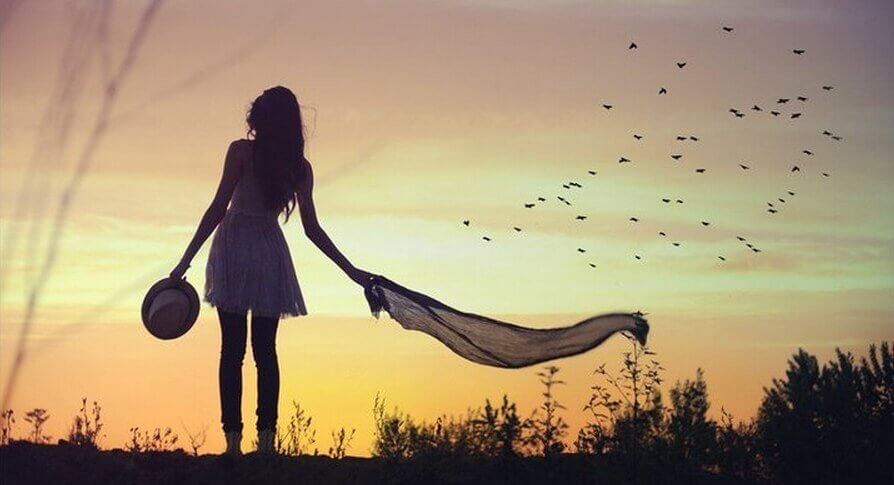 Een vrouw buiten met vogels in de lucht