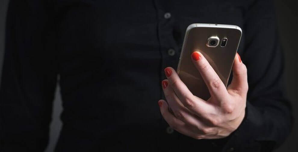 Vrouwenhand met rode nagels houdt haar smartphone vast
