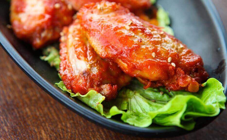 Kippenvleugeltjes in barbecuesaus op een bedje sla