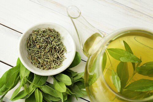 Kopje groene thee en losse thee blaadjes