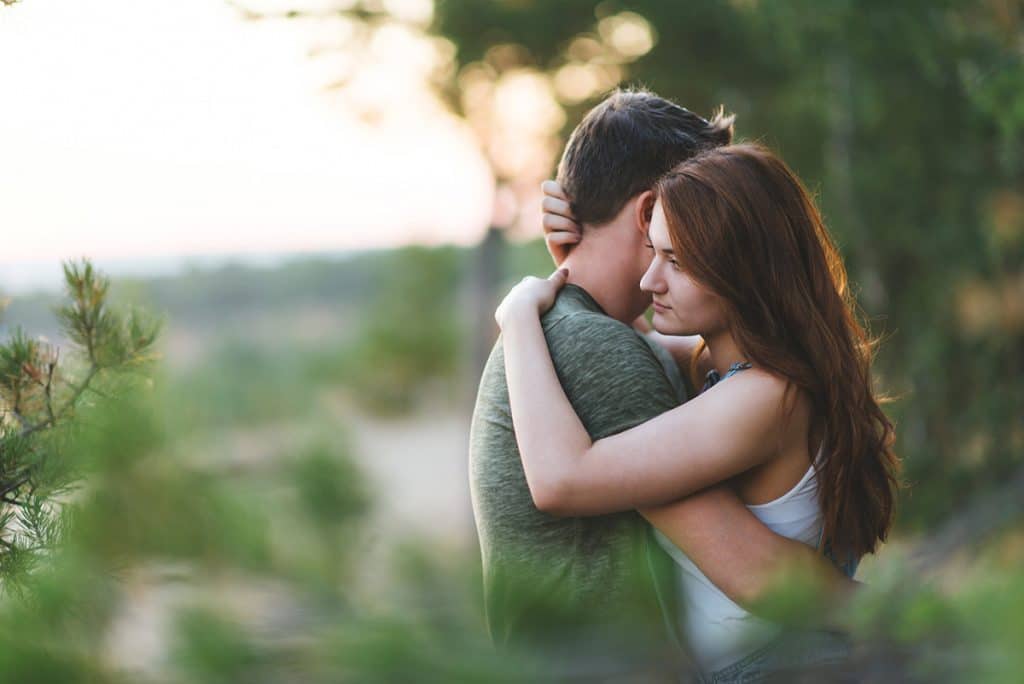 Vrouw kijkt afwezig voor zich uit, terwijl ze man vasthoudt