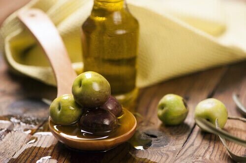Olijven en olijfolie op een houten lepel