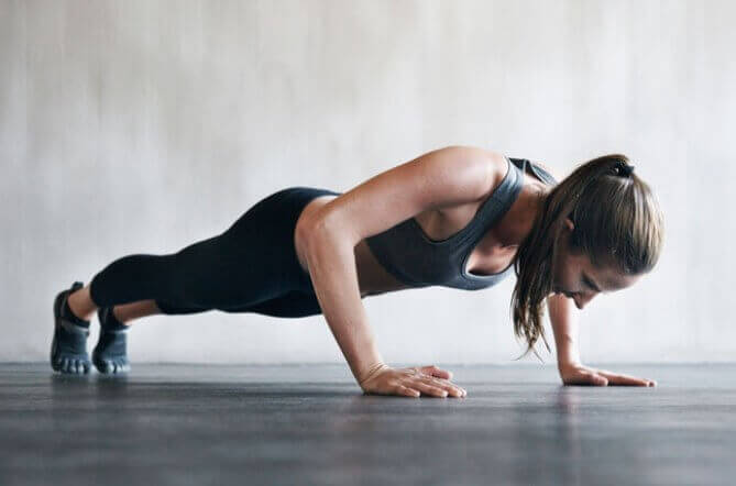 Vrouw in zwarte sportkleding doet push-ups