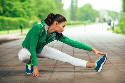 Vrouw in groen en wit sportpak is aan het rekken