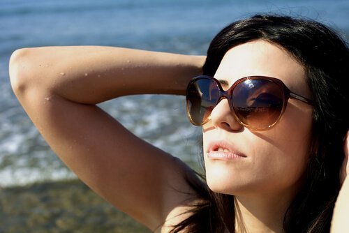 Vrouw in de zon op het strand met zonnebril