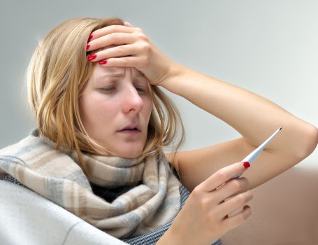 Vrouw houdt haar hoofd en een thermometer vast