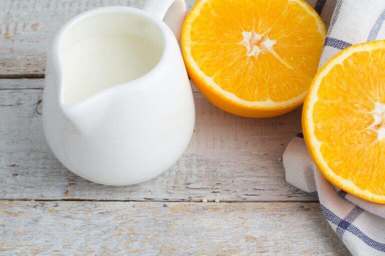 Gesneden sinaasappel en witte koffiekan met melk