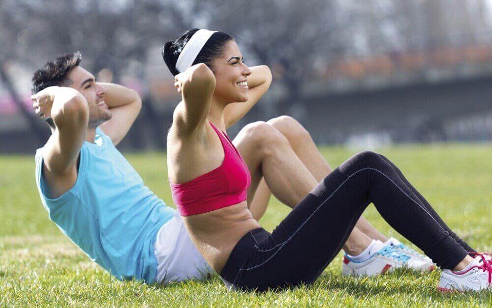 Man en vrouw in sportkleding doen sit-ups