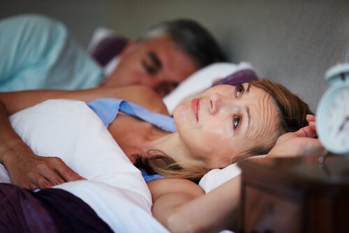 De man slaapt, de vrouw staart naar het plafond