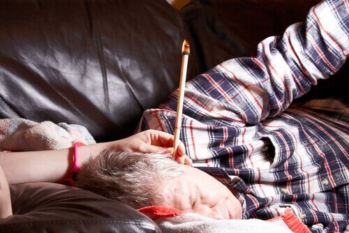 Man ligt op de bank met brandende oorkaars in zijn oor