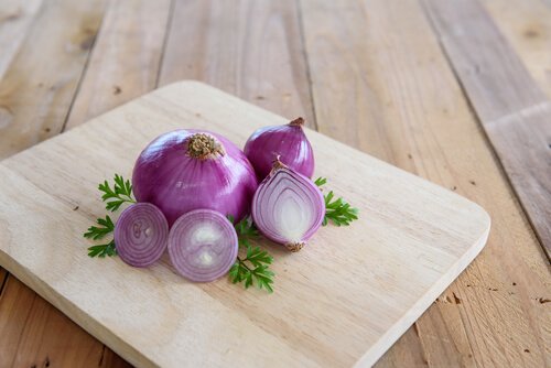 Snijplank met gesneden en hele rode ui