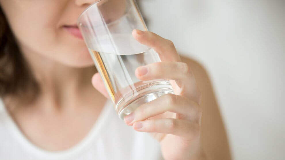 Vrouw met een wit shirt drint een glas water