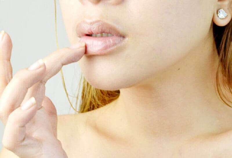 Vrouw voelt met vinger aan haar droge lippen