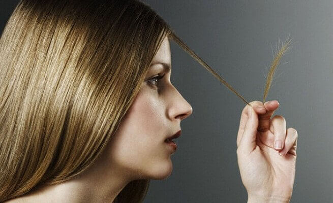 Meisje dat naar haar gespleten haarpuntjes kijkt