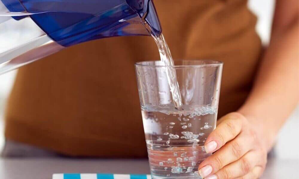 Vrouw die een glas mineraalwater voor zichzelf inschenkt