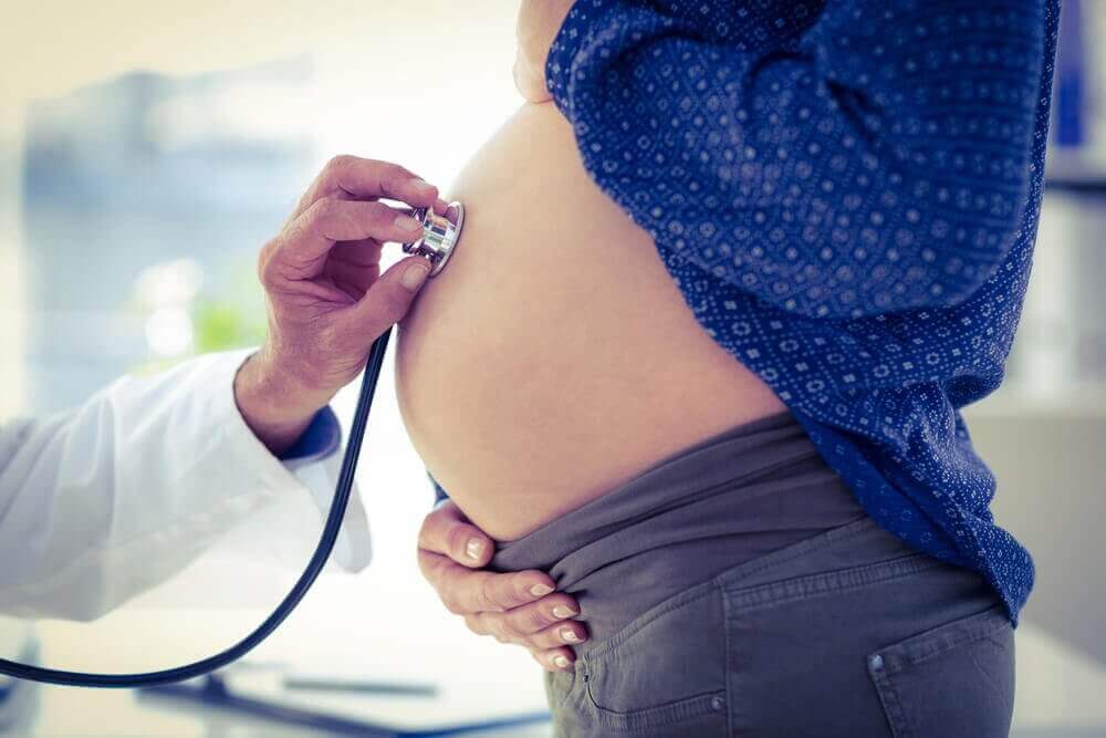 Dokter beluistert een zwangere buik