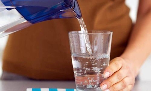 Vrouw schenkt glas water in