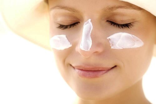 vrouw die lacht met zonnebrandcreme op haar gezicht