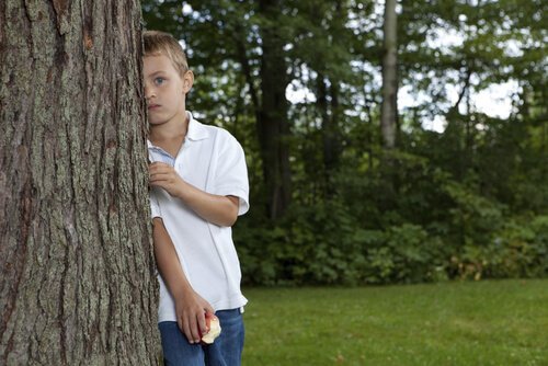 kind verstopt zich achter een boom