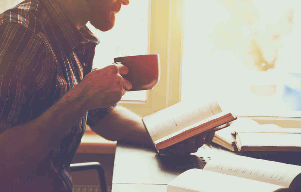 man met koffie leest een boek