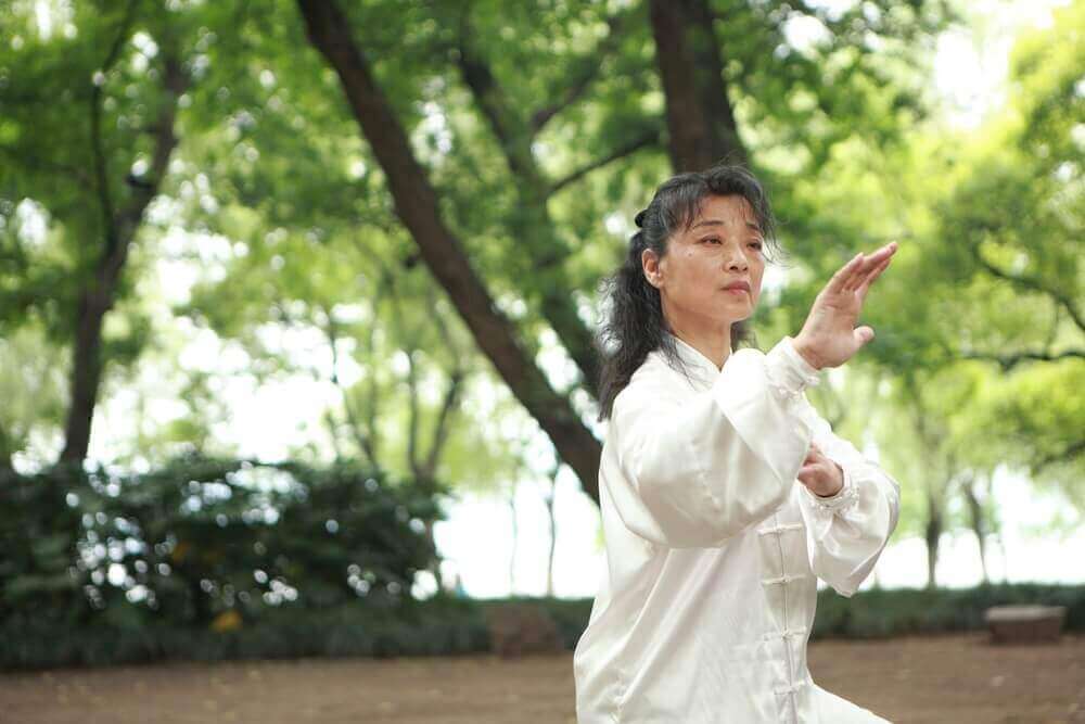 vrouw doet aan tai chi in het bos