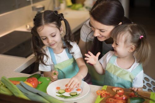 Moeder en meisjes die samen groenten snijden