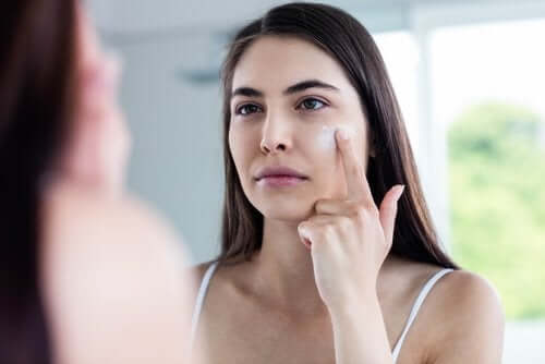 Een vrouw brengt crème aan op haar gezicht
