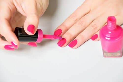 Een vrouw doet roze nagellak op haar nagels