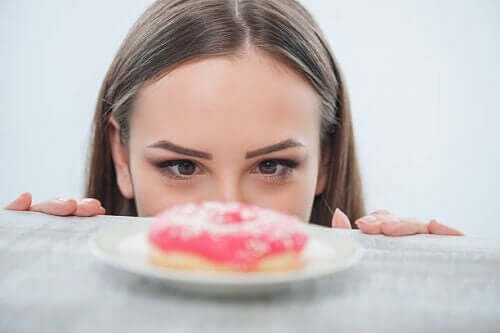 Vrouw staart naar donut en de verschillen tussen honger en angst
