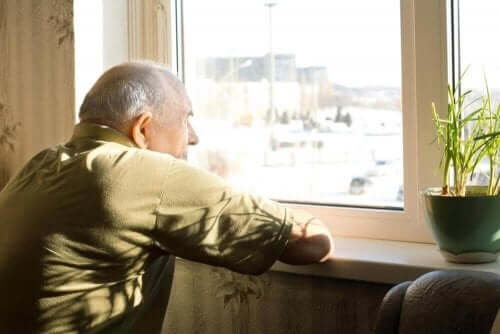 depressieve oude man kijkt uit het raam