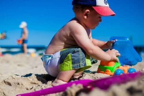 Jongen op het strand met speelgoedauto