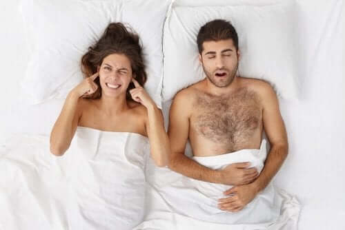 Een man snurkt en vrouw houdt vingers in haar oren