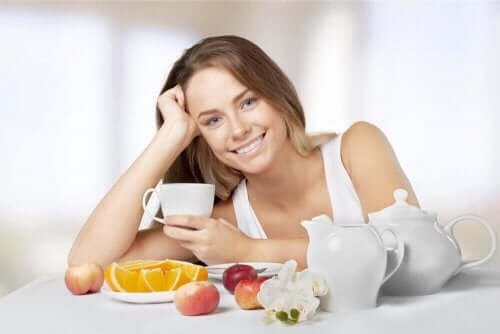 Een vrouw drinkt thee en eet fruit