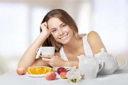 Een vrouw drinkt thee en eet fruit