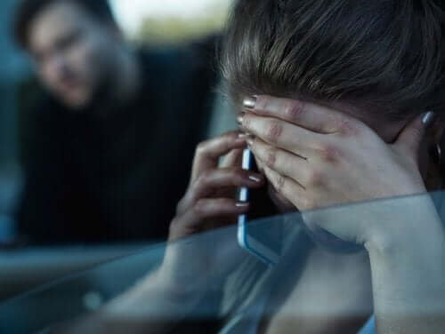 Een vrouw is aan de telefoon met haar hand voor haar gezicht