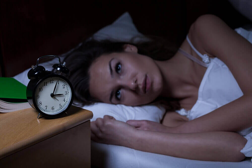 Vrouw ligt naar haar wekker te staren