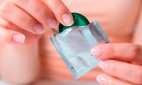 Een vrouw die een condoom uit de verpakking haalt